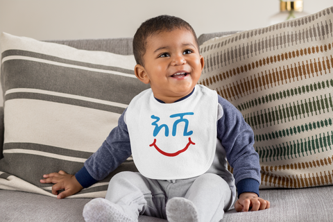 Baby wearing a bib that reads the Amharic wrod Eshi